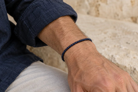 Man wearing a slim midnight navy seed bead bracelet beside a navy linen sleeve.
