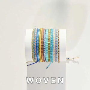 Colorful woven bracelets stacked on a white display cylinder in natural lighting