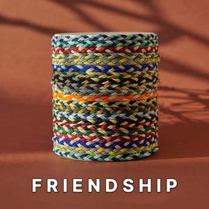 Friendship bracelets for sale stacked in a colorful woven pattern, showcasing a variety of vibrant, hand-braided cords on a neutral background.