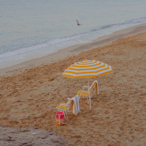 wristlet strap beside yellow striped umbrella and chairs on beach