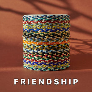 Friendship bracelets for sale stacked in a colorful woven pattern, showcasing a variety of vibrant, hand-braided cords on a neutral background.