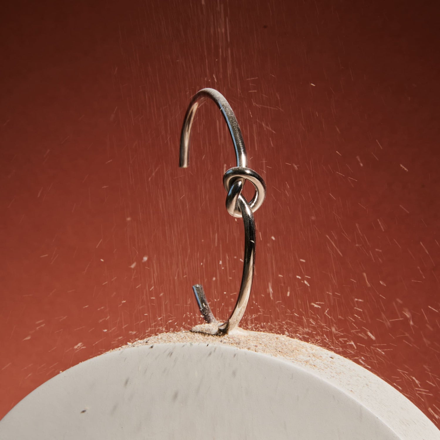 Close-up of silver bracelet with knot design for men on red background