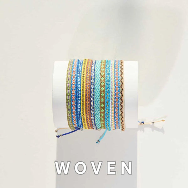 Colorful woven bracelets stacked on a white display cylinder in natural lighting