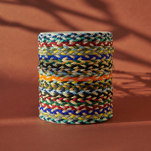 Stack of colorful handwoven bracelet cords in various patterns and tones