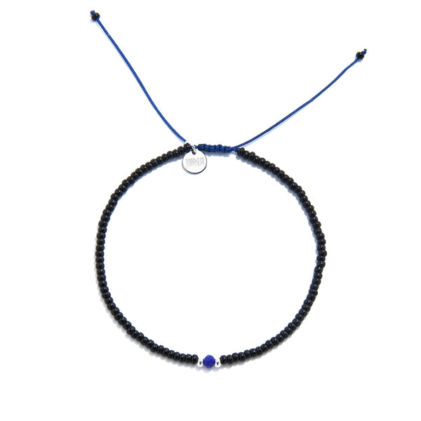 Flat lay of adjustable bead bracelet with black seed beads and blue accent on blue cord