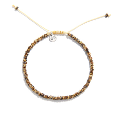 Flat lay of bead bracelet for men featuring earthy speckled beads and tan adjustable cord