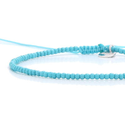 A detailed close-up of the adjustable sliding knot and silver charm on one of our light blue mens beaded bracelets.