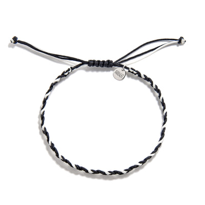 Flat lay of adjustable black and white friendship woven bracelet with charm tag and knot