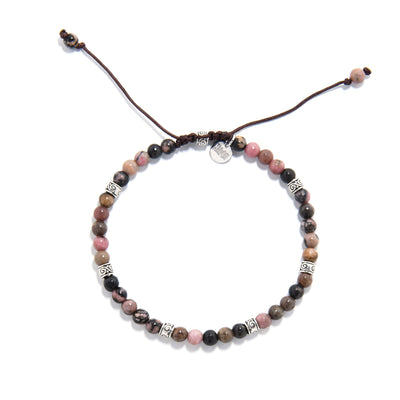 Top-down shot of a round rhodonite crystal bracelet, displaying a symmetrical arrangement of pink, black, and brown beads with metal detailing on a white background.