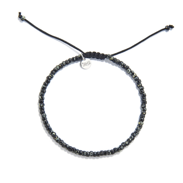 Flat lay of seed bead bracelet made with speckled black beads and black macrame closure