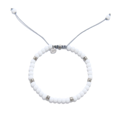 Overhead view of round white jade bracelet with adjustable drawstring and decorative metal beads.