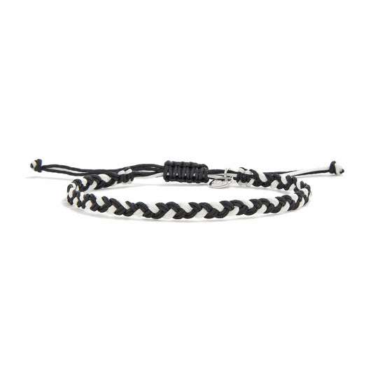 Black and white woven friendship bracelet with an adjustable sliding knot closure, featuring a silver charm. Designed to reflect bohemian style and Mediterranean charm, ideal for gifting or everyday wear.