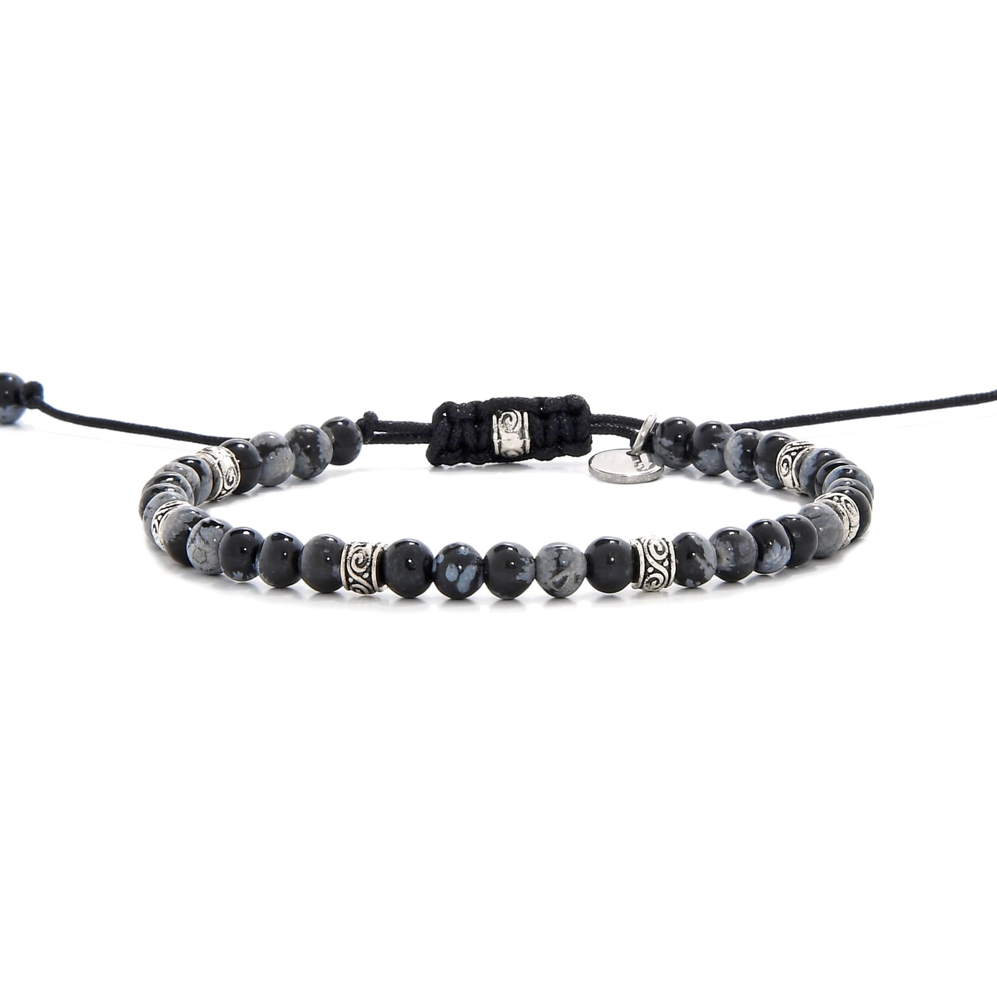 Full side view of the black stone bracelet laid out flat with black cord and adjustable clasp.
