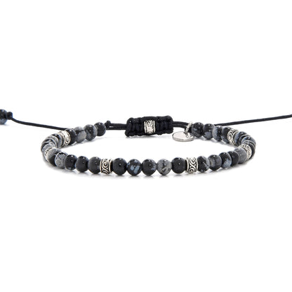 Full side view of the black stone bracelet laid out flat with black cord and adjustable clasp.