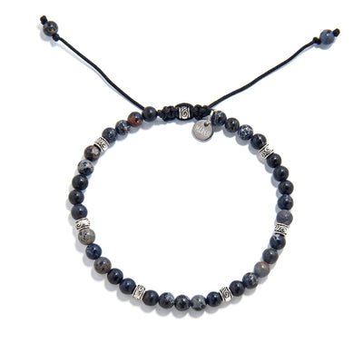 Black jasper beads bracelet with adjustable cord and metal charm, top view.