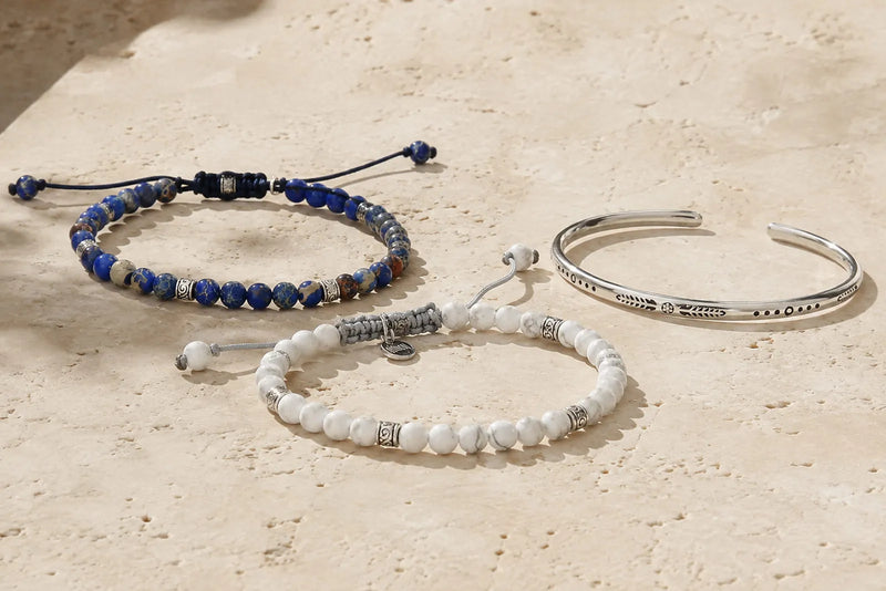 Black, white and silver bracelet color combo arranged naturally on light travertine