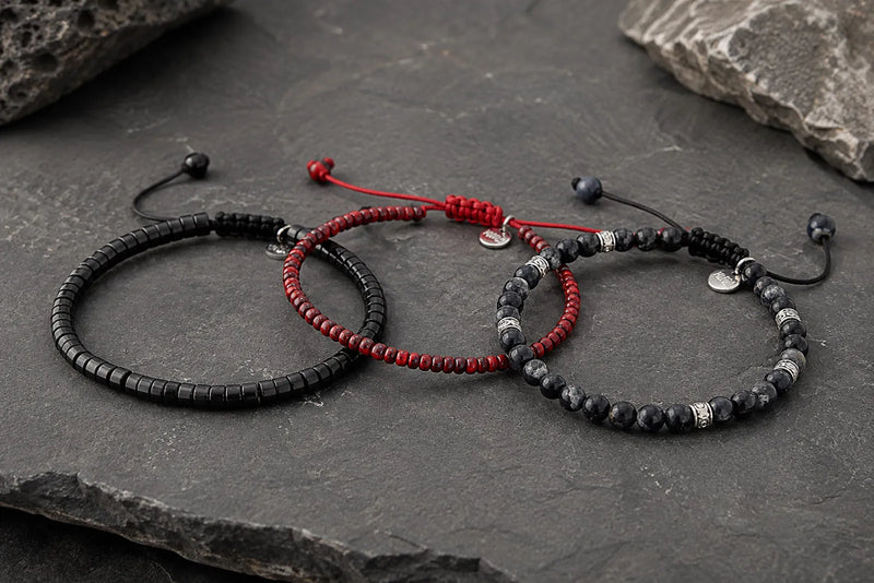 Black and red bracelet color combo featuring three men’s bracelets on dark stone