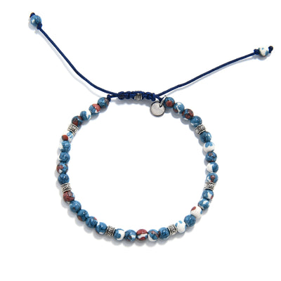 Top view of blue flower jasper bracelet showing round beads in blue, red, and white, with detailed silver accents and adjustable navy cord.

