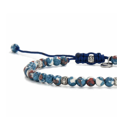 Close-up of blue jasper jewelry highlighting polished stone pattern, silver detailing, and adjustable blue cord knot.