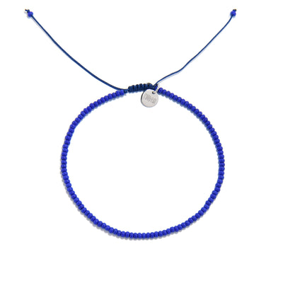 A top-down photo of a cobalt blue bracelet, an example of our stretch bead bracelets, arranged in a circle on a white background.