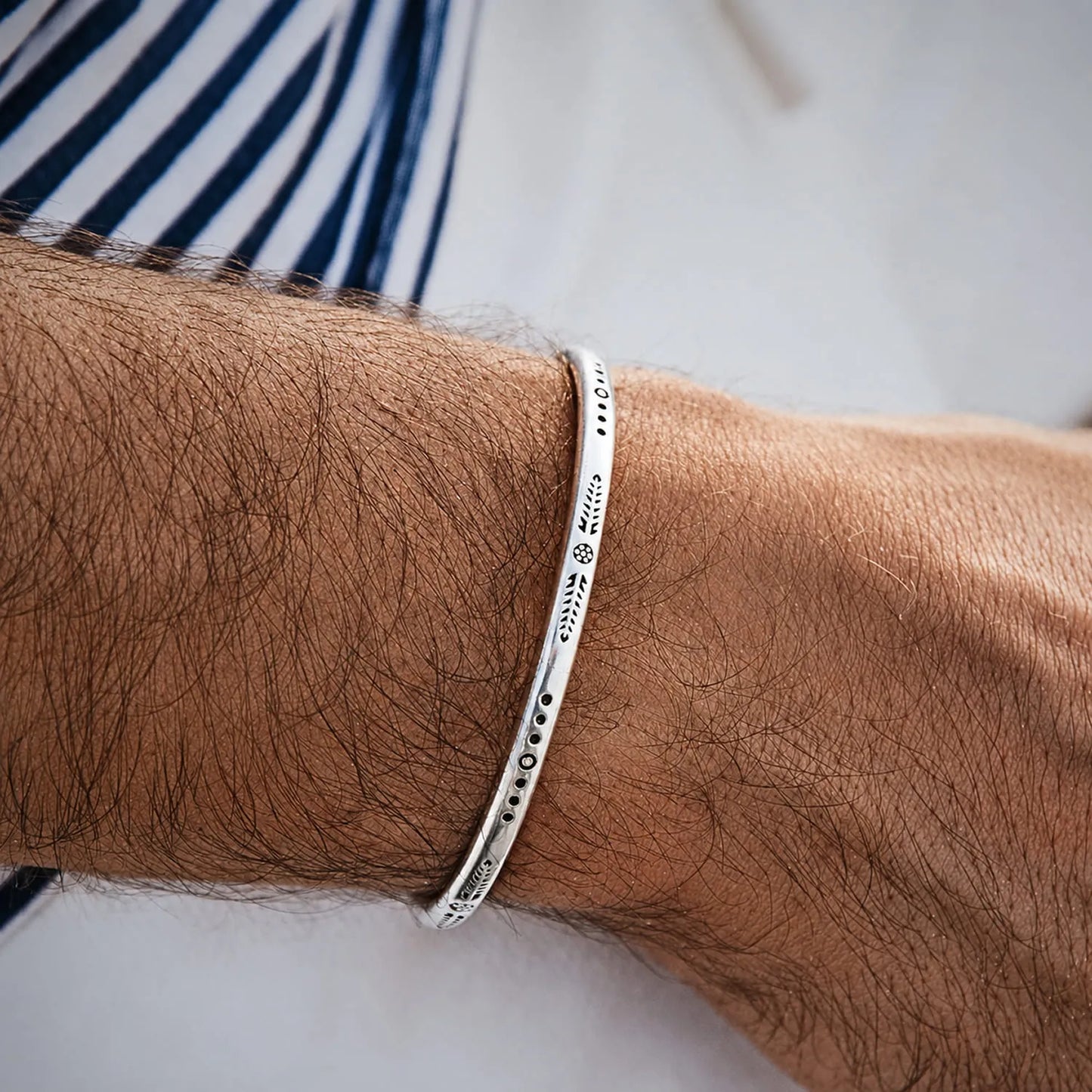 Bracelet Bangle Silver worn on wrist, showing slim polished band and engraved arrow detail