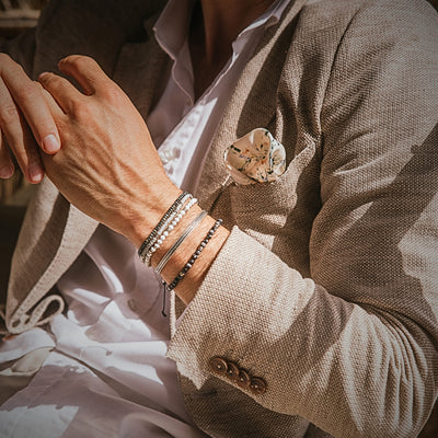 Cannes men's bracelet set styled with a neutral suit, showing layered silver and beaded bracelets