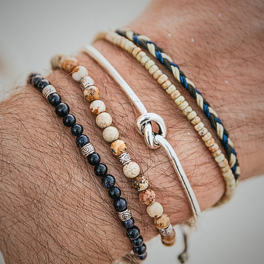 Detailed view of stacked Capri bracelets featuring beads and a silver knot.