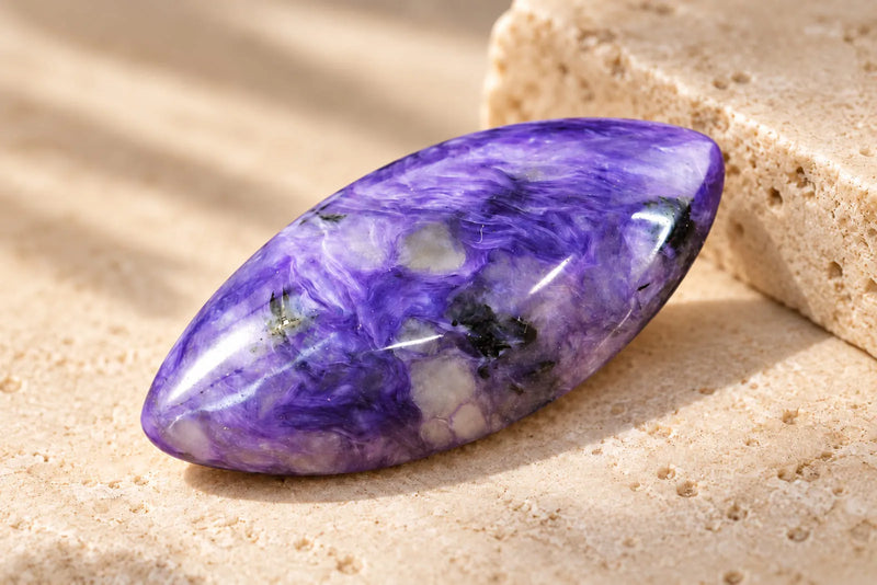Polished charoite purple gemstone with swirling violet, lavender and dark mineral patterns