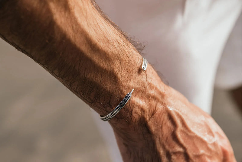 An open silver cuff bracelet sits securely around a man’s wrist with the decorative side visible.