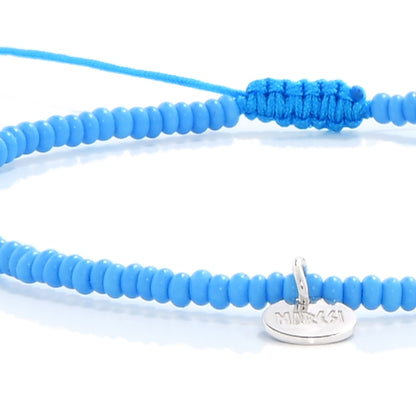 Close-up view of the Corte Seed Bracelet showing blue beads and silver cross detail on adjustable cord