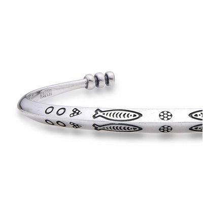 Close-up of cuff bracelet showing fish and circle engravings