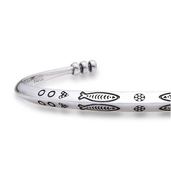 Close-up of cuff bracelet showing fish and circle engravings