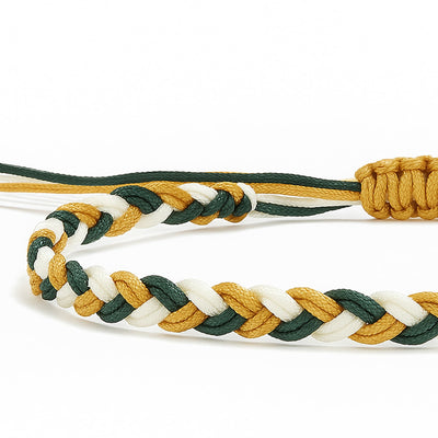 Close-up of a braided friendship bracelet with green, white, and gold colors for balance and harmony.