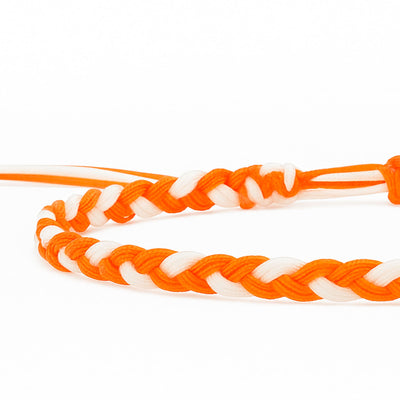 Close-up of orange and white friendship bracelet made with thread in braided design