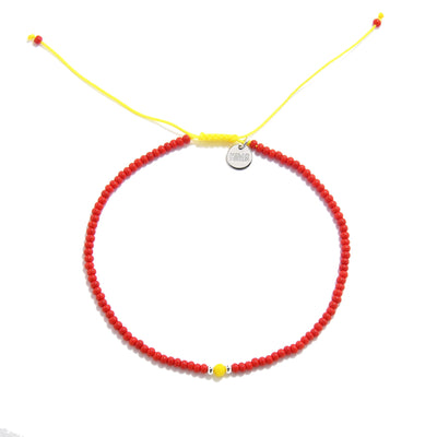  Flat-lay of red and yellow man bracelet beads with yellow cord