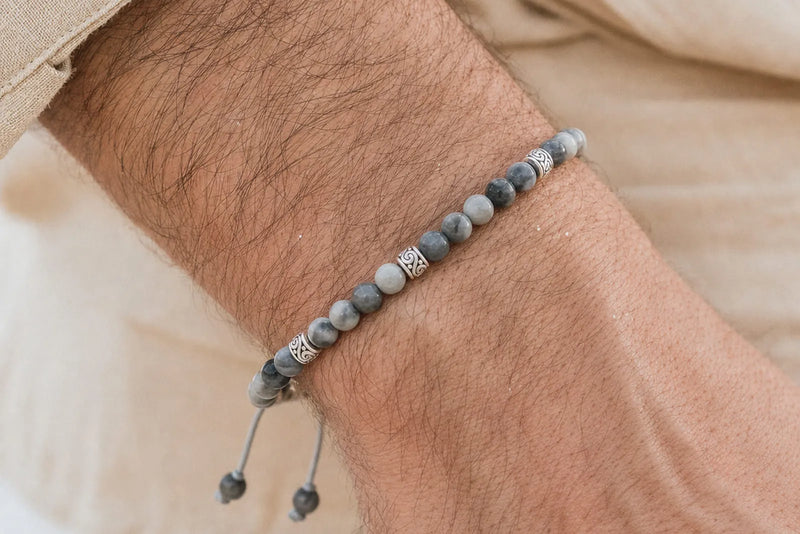 Gray Stone Jewelry bracelet with polished gray beads and engraved silver spacers on a man’s wrist.