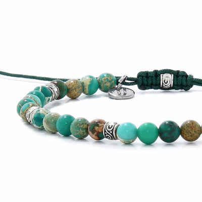 Side view of Green Jasper Bracelet with turquoise beads, patterned stones, silver spacers, and green cord.