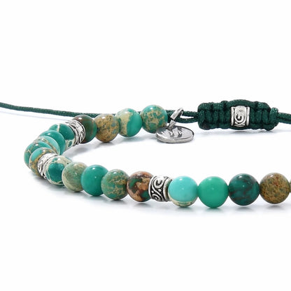 Side view of Green Jasper Bracelet with turquoise beads, patterned stones, silver spacers, and green cord.