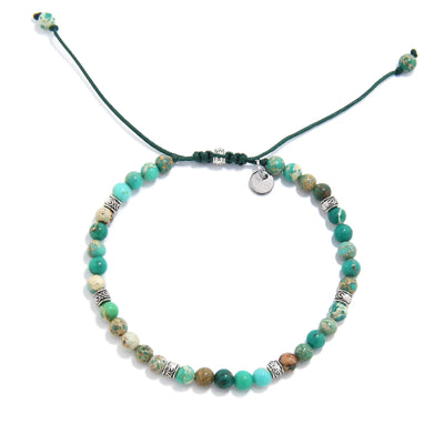 Top view of Green Jasper Bracelet with mixed green beads, silver spacers, green cord, and charm.