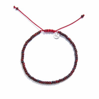 Flat lay of handmade beads bracelet with deep red seed beads and red sliding knot