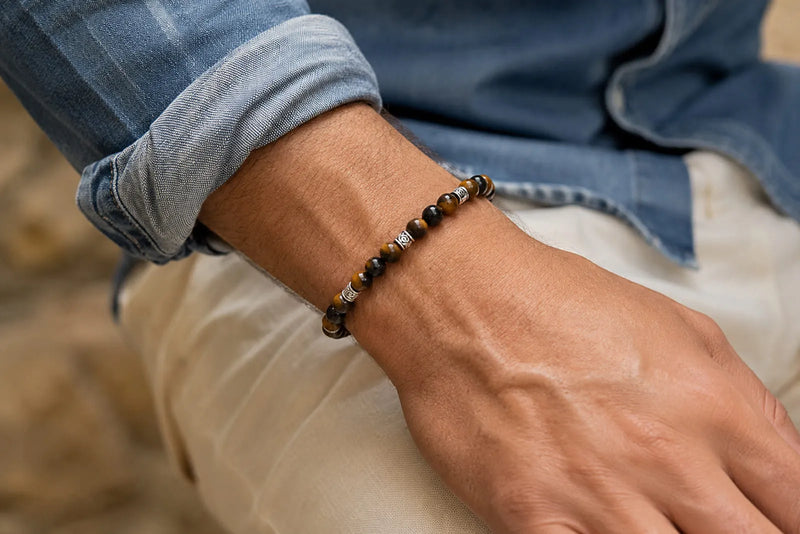 Close up of a Tiger Eye men’s bracelet worn comfortably above the wrist with a denim shirt.