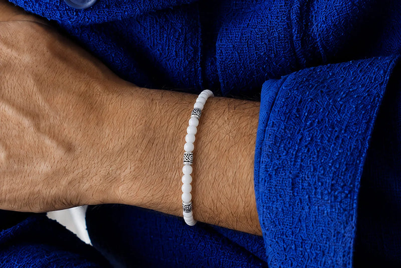 Jade Bracelet Beads worn on a man’s wrist with white round beads, silver spacers, and a textured blue shirt