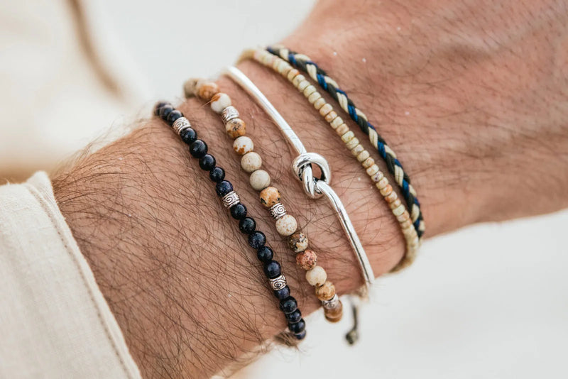Jasper Jewelry bracelets with cream and dark stone beads styled in a layered men’s wrist stack with silver details.