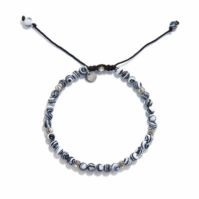 Malachite bracelet laid flat, showing circular pattern and woven cord clasp