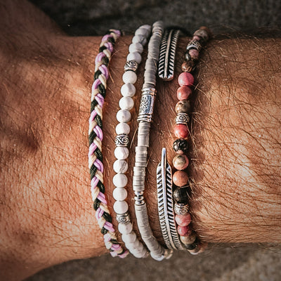  Stack of Mallorca bracelets on wrist, highlighting silver accents, white and pink beads, and braided cord.