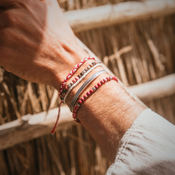 Close-up of stacked Marseille bracelet set with red, silver, and beaded designs on wrist