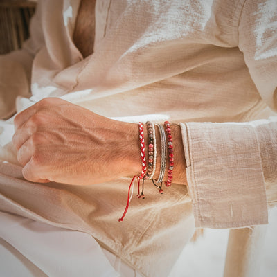 Man wearing Marseille bracelet set with red and natural-toned stacks bracelets