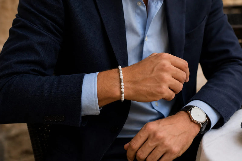 Close up of a navy blazer, pale blue shirt, WHITE bracelet and classic watch styled for cocktail attire
