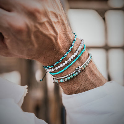 Turquoise jewelry styled on wrist with layered bead bracelets in white and blue tones.