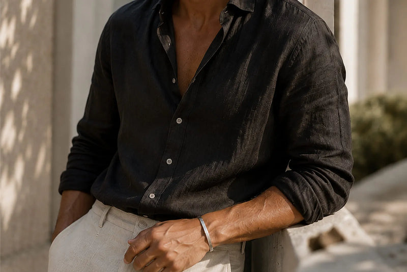 Men’s summer style featuring a black linen shirt, light trousers and a slim silver cuff bracelet.